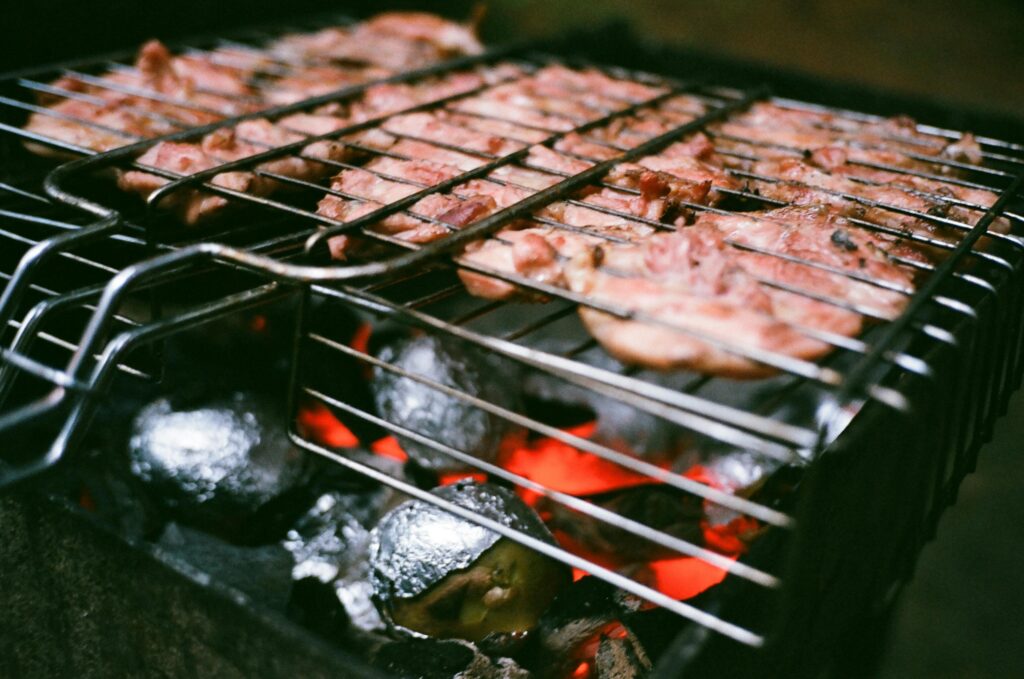 Close-up of sizzling meat grilling over hot coals, perfect for BBQ enthusiasts.